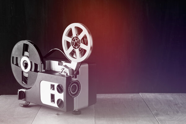 old 8mm Film Projector over wooden table and textured background