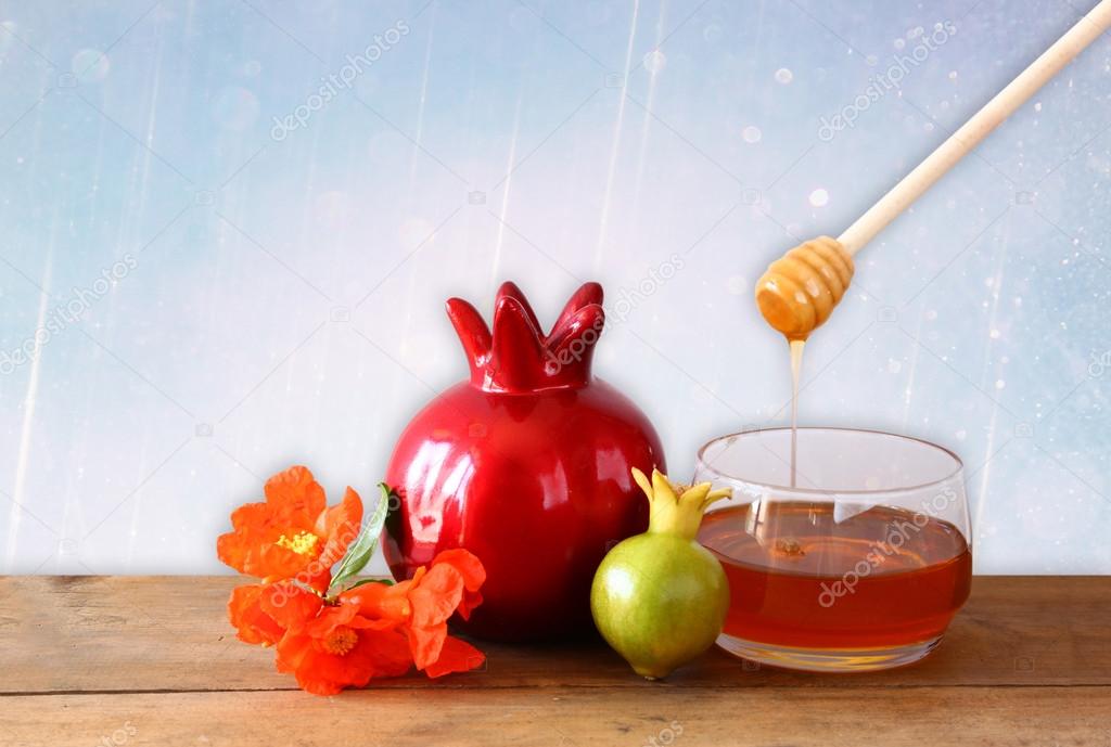 rosh hashanah (jewesh holiday) concept - honey and pomegranate over wooden table. traditional holiday symbols.