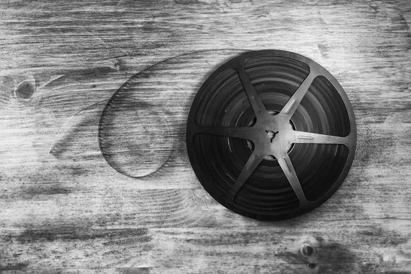 top view image of old 8 mm movie reel over wooden background. black and white photo