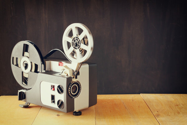 old 8mm Film Projector over wooden table and textured background