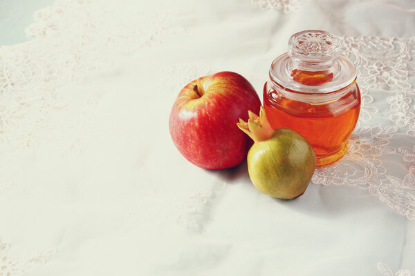 rosh hashanah (jewesh holiday) concept - honey, apple and pomegranate over wooden table. traditional holiday symbols.