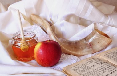 rosh hashanah (jewesh holiday) concept - shofar, torah book, honey, apple and pomegranate over wooden table. traditional holiday symbols.