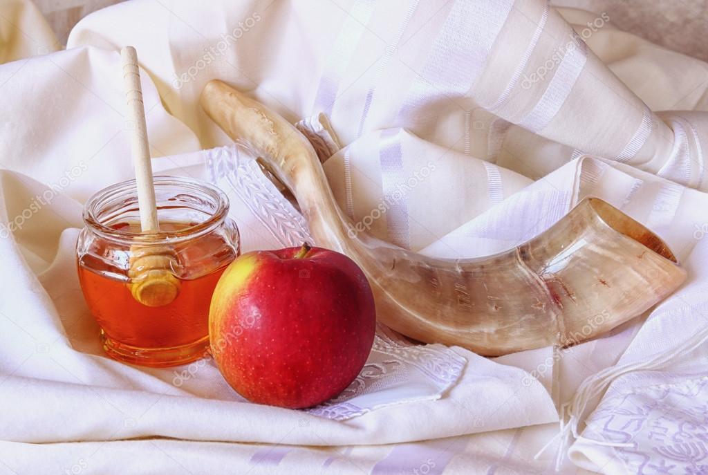 rosh hashanah (jewesh holiday) concept - shofar, honey, apple and pomegranate over wooden table. traditional holiday symbols.