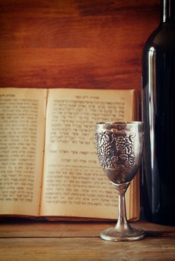 vintage shabbath silver cup of wine in front of torah prayer book
