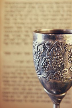 vintage shabbath silver cup of wine in front of torah prayer book