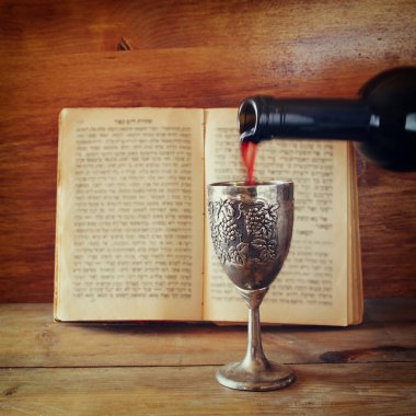 vintage shabbath silver cup of wine in front of torah prayer book