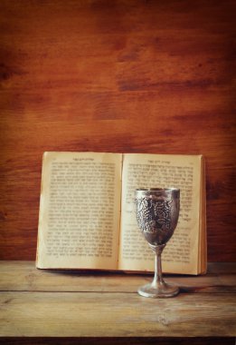 vintage shabbath silver cup of wine in front of torah prayer book