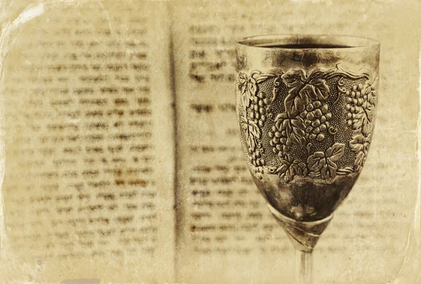 Vintage shabbath silver cup of wine in front of torah prayer book. old photo style image — Stock fotografie