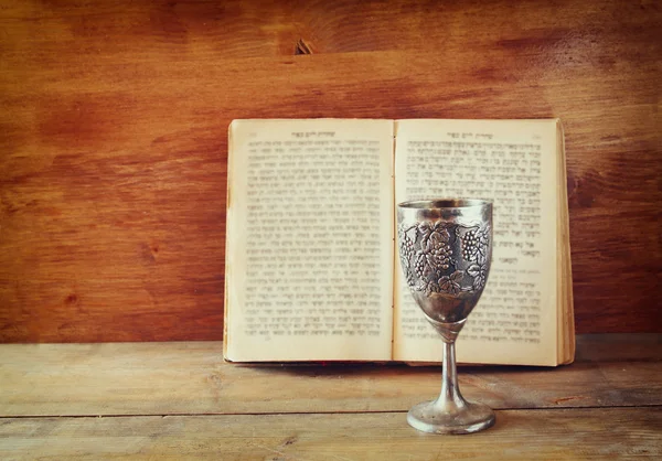 vintage shabbath silver cup of wine in front of torah prayer book
