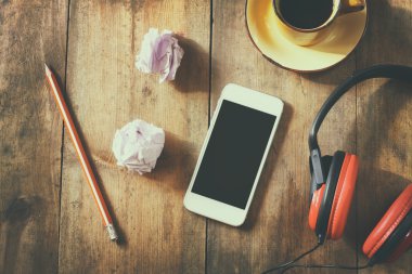 top view image of smartphone with blank screen headphones and coffee cup. room for text . faded style image