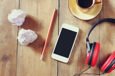 top view image of smartphone with blank screen headphones and coffee cup. room for text . faded style image