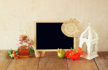 Rosh hashanah (jewesh tatil) kavramı - blackboard, bal, elma ve nar ahşap masa üzerinde. geleneksel tatil sembolleri.