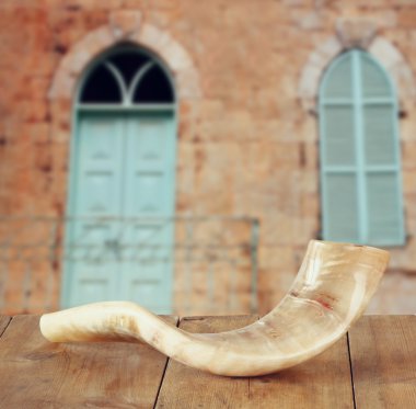 shofar (horn) on wooden table in front of jerusalem ancient window. rosh hashanah (jewish holiday) concept . traditional holiday symbol. clipart