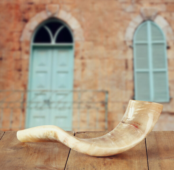 shofar (horn) on wooden table in front of jerusalem ancient window. rosh hashanah (jewish holiday) concept . traditional holiday symbol.