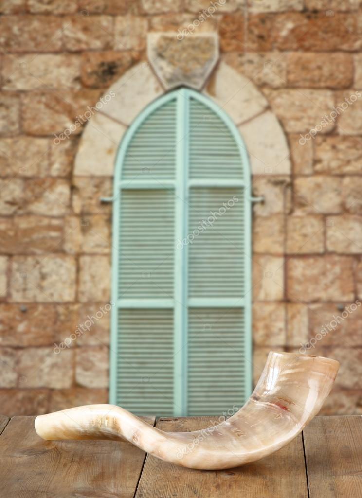 Shofar (horn) on wooden table in front of jerusalem ancient window