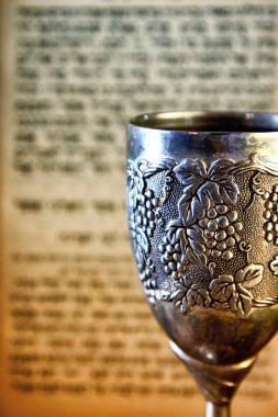 vintage shabbath silver cup of wine in front of torah prayer book