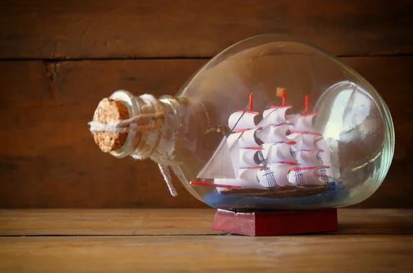 Изображение декоративной лодки в бутылке на деревянном столе. морская концепция — стоковое фото