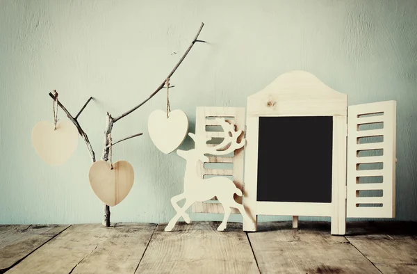 Decorative chalkboard frame and wooden hanging hearts over wooden table. ready for text or mockup — Stock Photo, Image