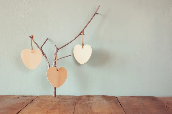 Hanging wooden hearts over wooden background — Stock Photo, Image