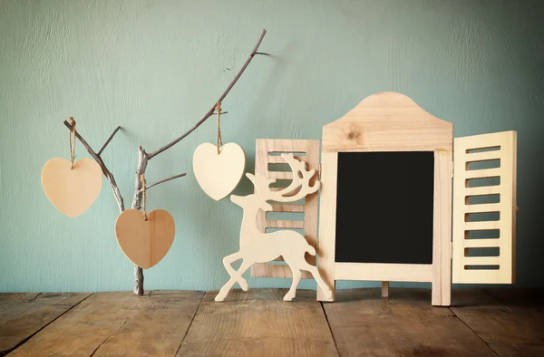 Cadre de tableau noir décoratif et des cœurs suspendus en bois sur la table en bois. prêt pour le texte ou la maquette — Photo