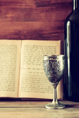 vintage shabbath silver cup of wine in front of torah prayer book