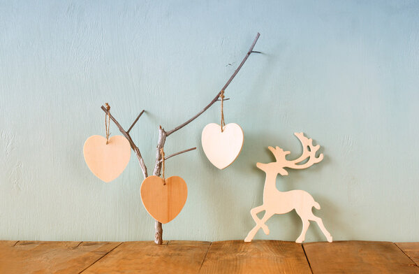 подвесить деревянные сердца над и деревянные олени украшения оленя на деревянном фоне. ретро фильтрованное изображение
