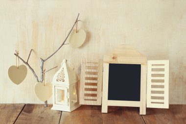Dekoratif kara tahta çerçeve ve ahşap masa üzerinde ahşap asılı kalpler. metin veya mockup için hazır