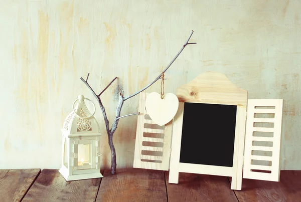 Decorative chalkboard frame and wooden hanging hearts over wooden table. ready for text or mockup — Stock Photo, Image