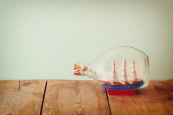 Imagem de barco decorativo na garrafa na mesa de madeira. conceito náutico. imagem retro filtrada — Fotografia de Stock