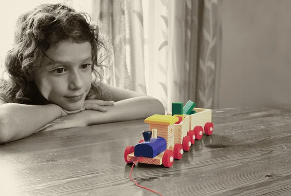 Kid looking at wooden train