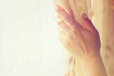 Woman's hand opening curtains