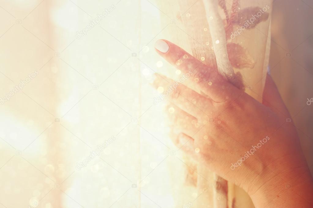 Woman's hand opening curtains