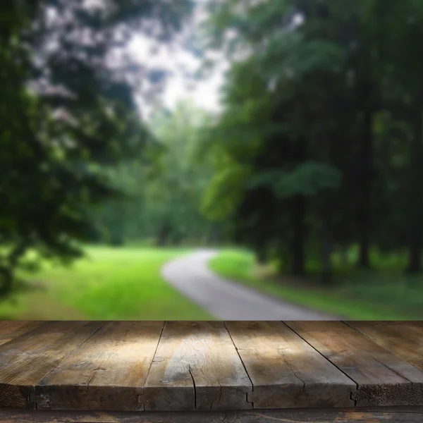 Meja papan kayu antik di depan pemandangan hutan yang indah dan abstrak — Stok Foto