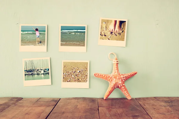 Мгновенные фотографии висят на деревянном текстурированном фоне рядом с декоративной морской звездой. ретро фильтрованное изображение — стоковое фото