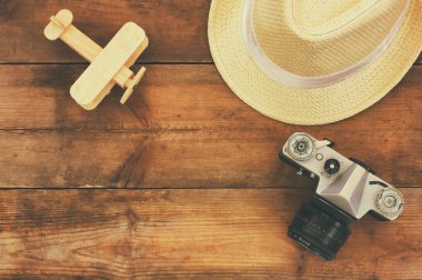 top view image of wood aeroplane, fedora hat and old camera over wooden table