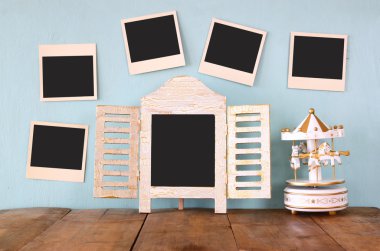 blank instant photos hang over wooden textured background next to blank blackboard and vintage white carousel horses