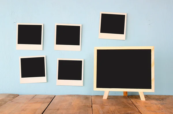 Fotos instantâneas em branco pendurar sobre fundo texturizado de madeira ao lado de quadro preto em branco — Fotografia de Stock