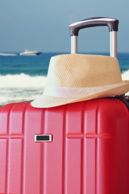 Kırmızı zarif seyahat Bagaj ve fedora şapka önündeki deniz görüntüsü. seyahat ve tatil kavramı