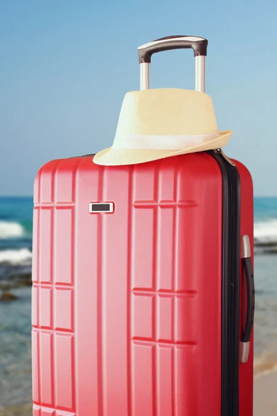 Image of red elegant travel luggage and fedora hat  in front of sea. travel and vacation concept — Stock Photo, Image