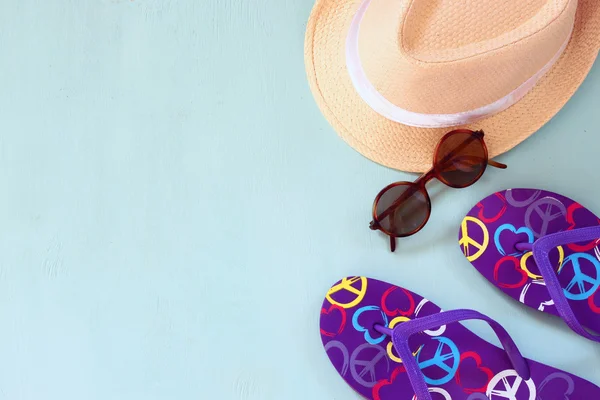 Colorful flip flops fedora hat and sunglasses on wooden background — ストック写真