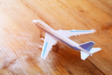 toy airplane and passport over wooden table. faded style image