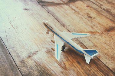 toy airplane and passport over wooden table. faded style image