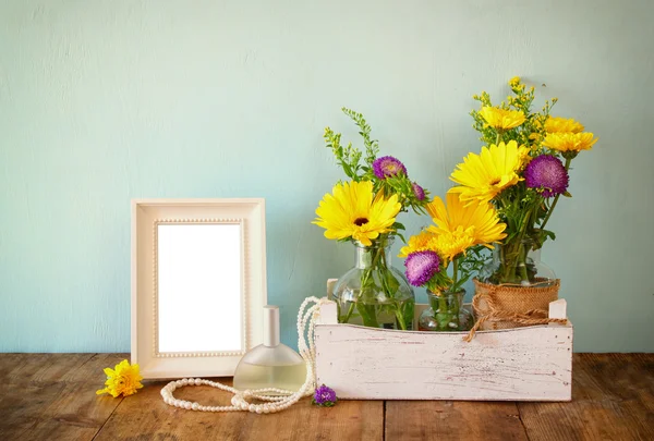 Letní kytice květin vedle prázdného Dobová fotografie rám na dřevěný stůl s mátou pozadím. Vintage filtrovaného obrazu — Stock fotografie