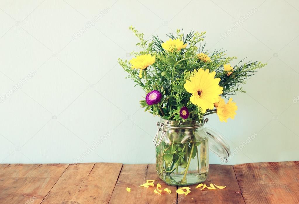 summer bouquet of flowers on the wooden table with mint background. vintage filtered image