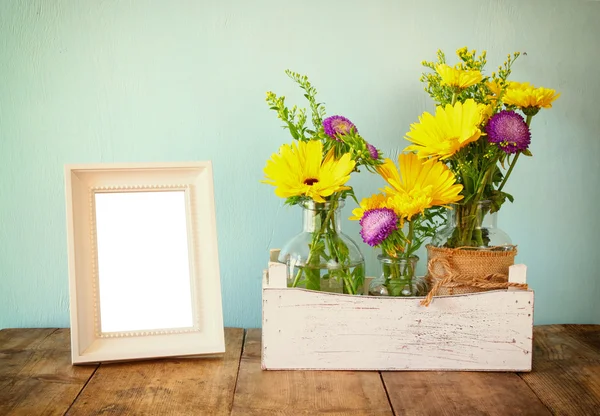 Letní kytice květin vedle prázdného Dobová fotografie rám na dřevěný stůl s mátou pozadím. Vintage filtrovaného obrazu — Stock fotografie