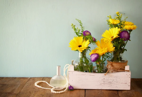 Bouquet estivo di fiori accanto alla cornice fotografica vintage vuota sul tavolo in legno con sfondo menta. immagine filtrata vintage — Foto Stock