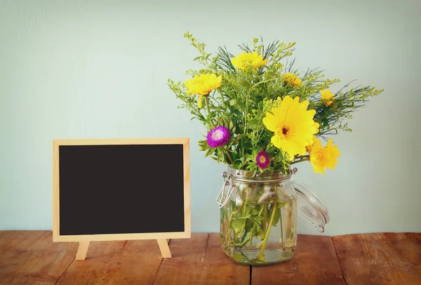 Bouquet estivo di fiori e lavagna di legno sul tavolo di legno. copia spazio — Foto Stock