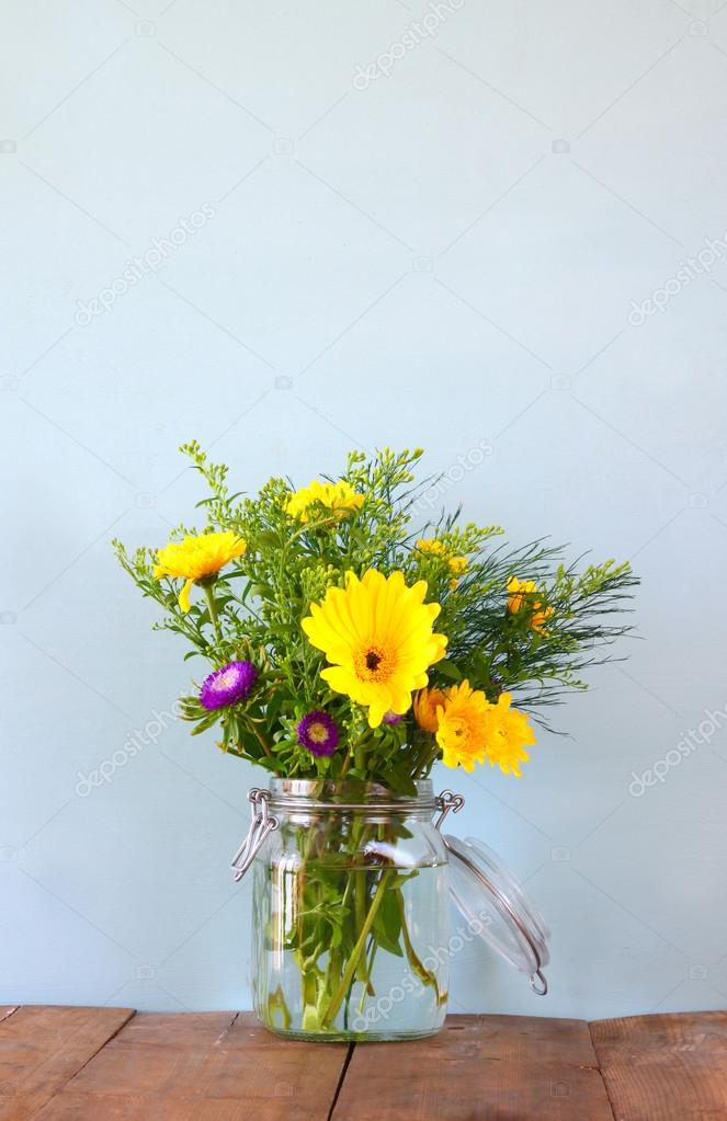 summer bouquet of flowers on the wooden table with mint background. vintage filtered image