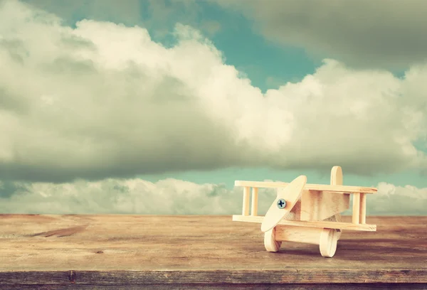 Imagen de avión de juguete de madera sobre mesa de madera contra el cielo nublado — Foto de Stock