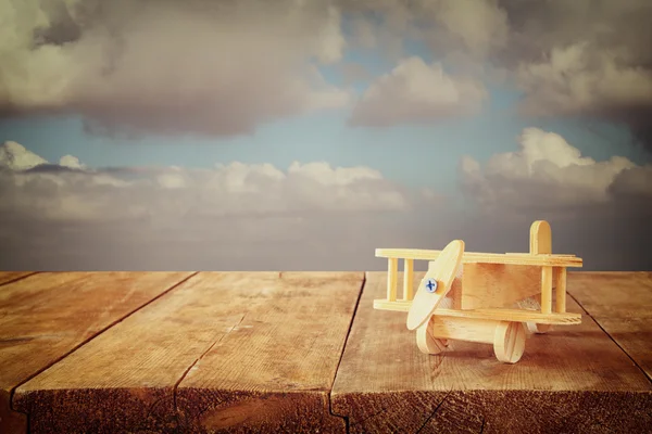 Imagen de avión de juguete de madera sobre mesa de madera contra el cielo nublado — Foto de Stock